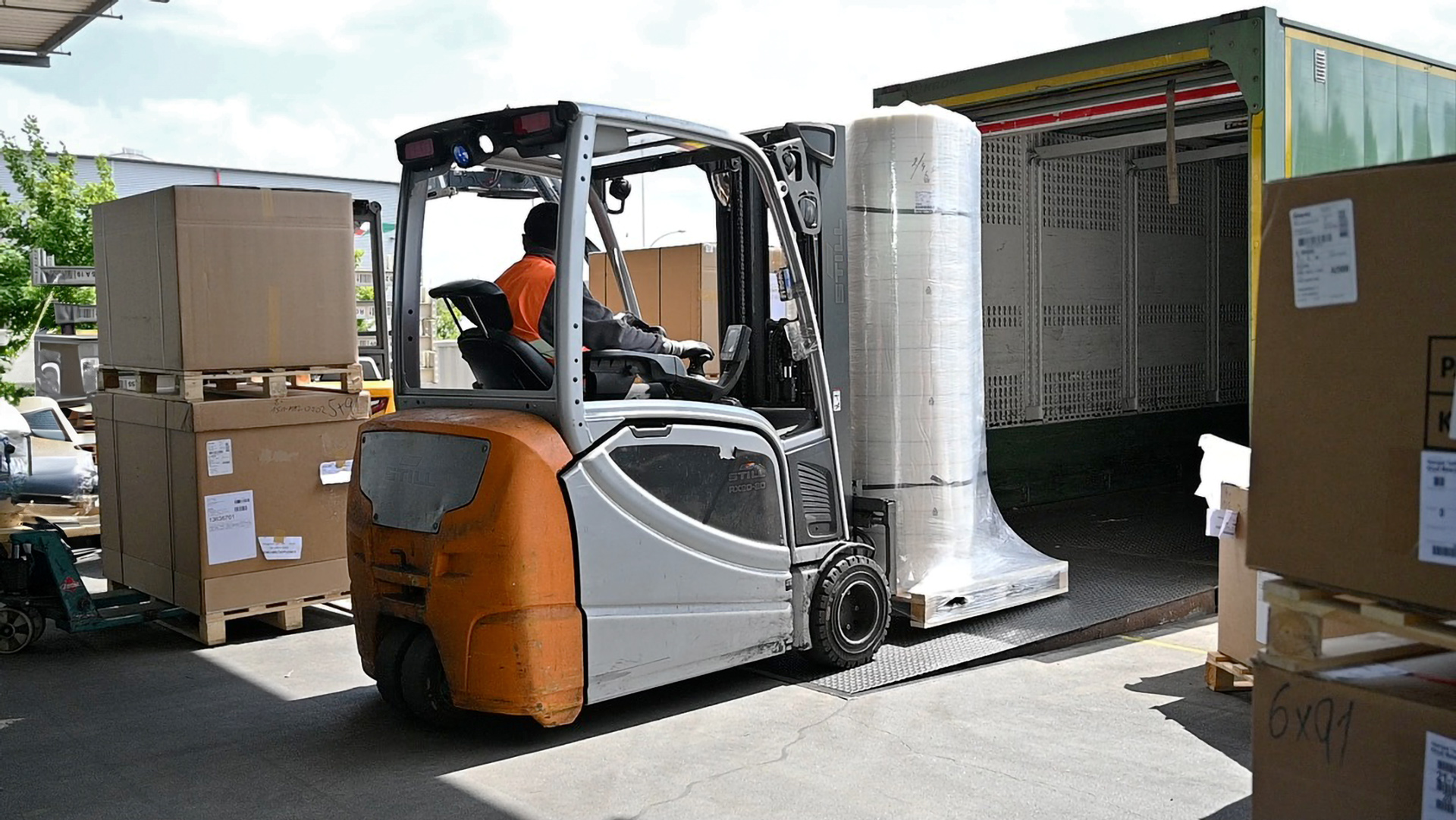 Gabelstapler lädt Rollenware auf Palette in Lkw-Anhänger an Logistikrampe